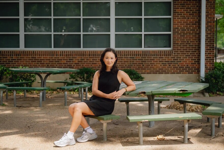 A woman sits at a picnic table outside.