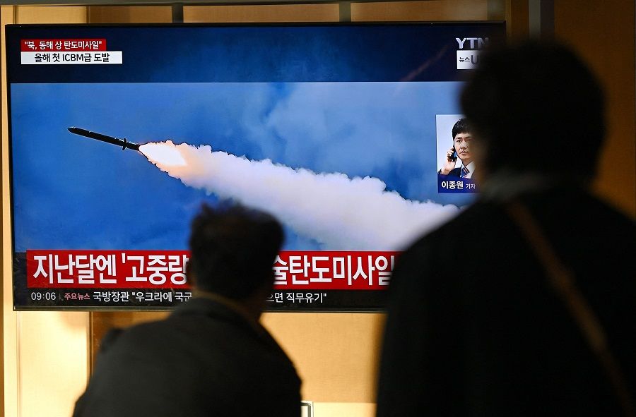 People watch a television screen showing a news broadcast with file footage of a North Korean missile test, at a train station in Seoul on 31 October 2024. (Jung Yeon-je/AFP)