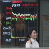 A woman passes by a stock index at a brokerage in Beijing, Wednesday.