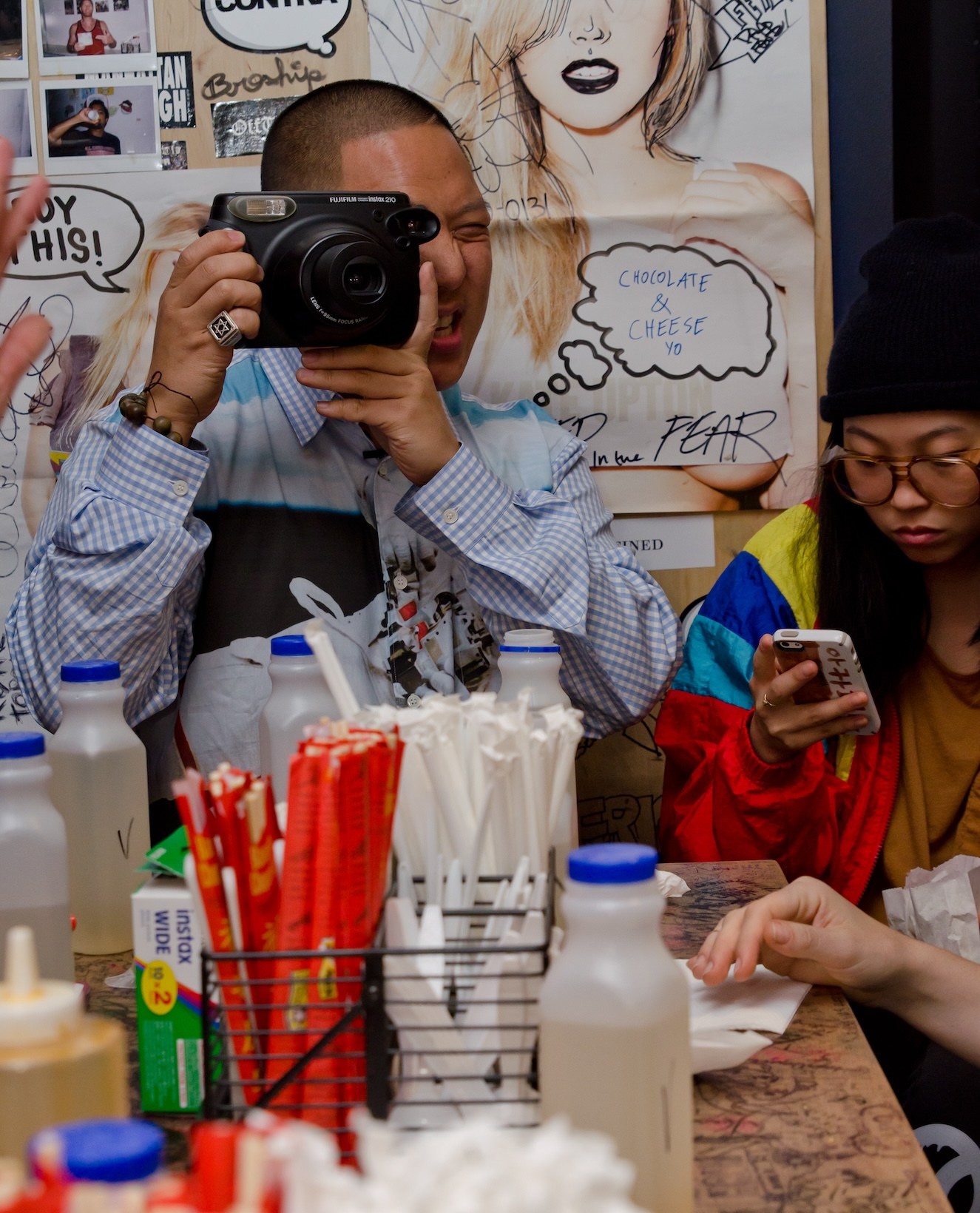 Chef and author Eddie Huang using an instant camera at a dining table inside Baohaus.